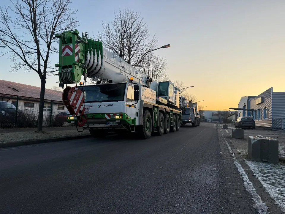 Autokran auf einer Straße im Gewerbegebiet bei Sonnenaufgang
