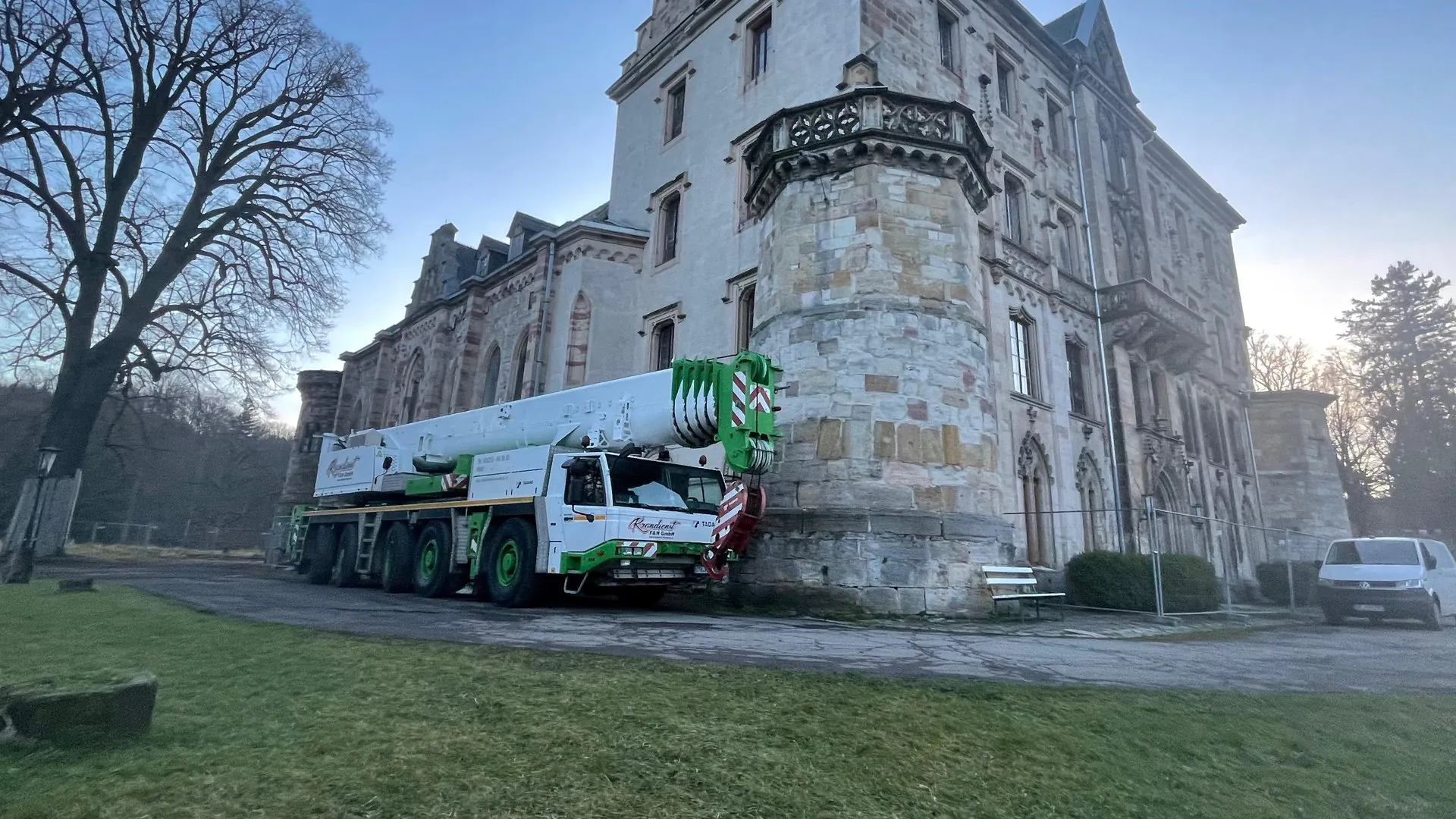 Weiß-grüner Autokran von Krandienst F&H vor einem Schlossgebäude aus Sandstein
