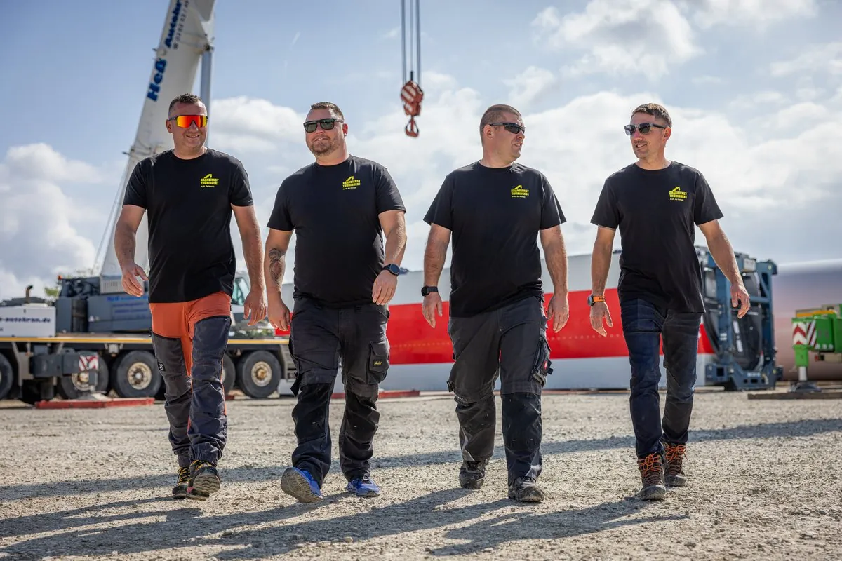 Vier Mitarbeiter von Krandienst Thüringen gehen über eine Baustelle mit Autokranen